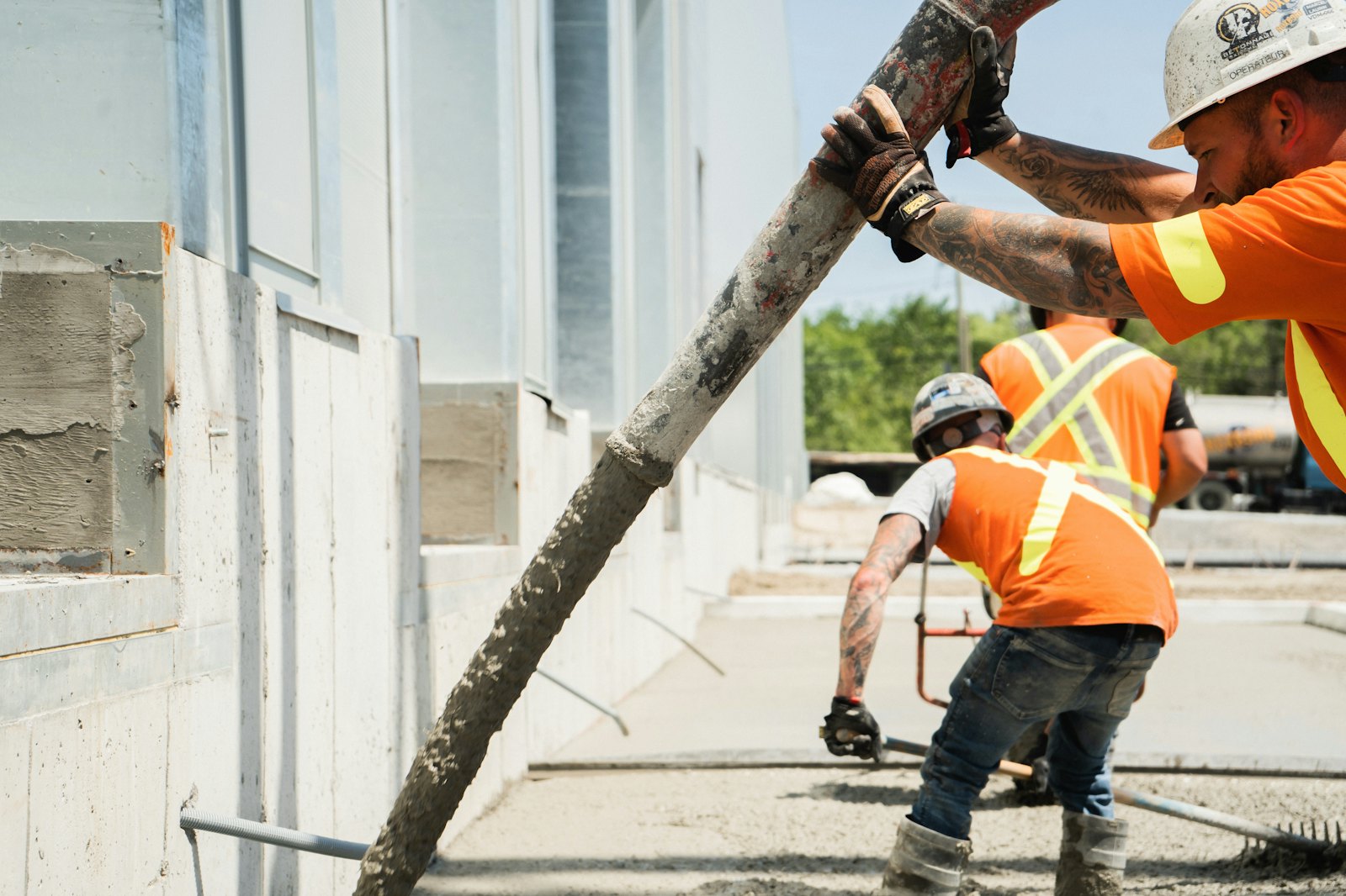 Concrete crew in orange hi-vis working a pump line on a Sydney site