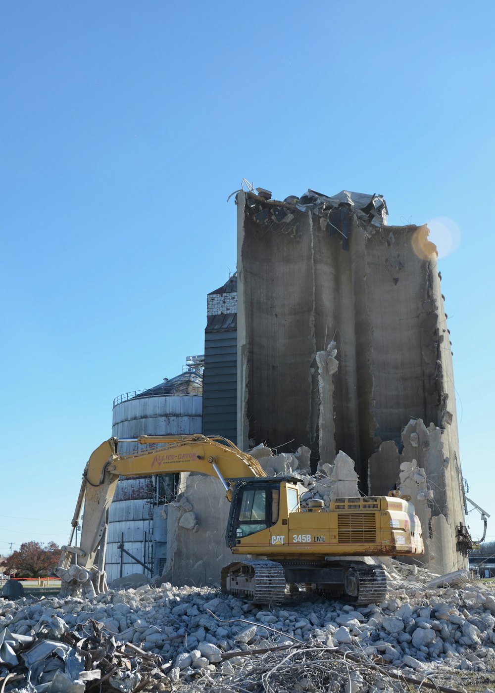 Excavator working at the base of a partly demolished concrete silo